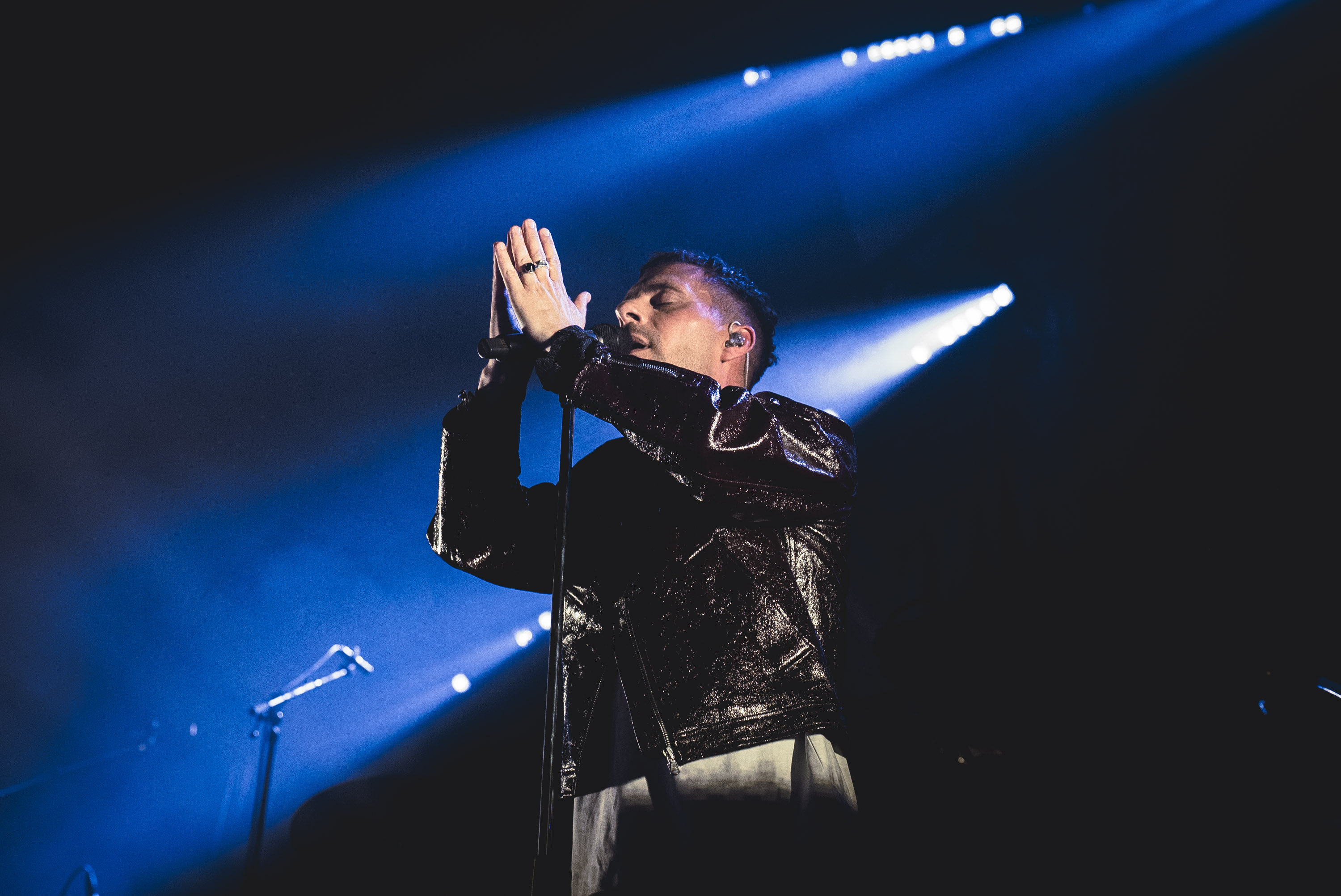 Oskar Linnros at the microphone under blue stage lighting